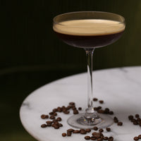 Cocktail in a glass with coffee beans on a marble surface - Ready to drink cocktails - tequila espresso martini