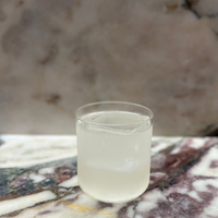 Clear glass of liquid on a marble surface with a marble background ready to drink cocktails