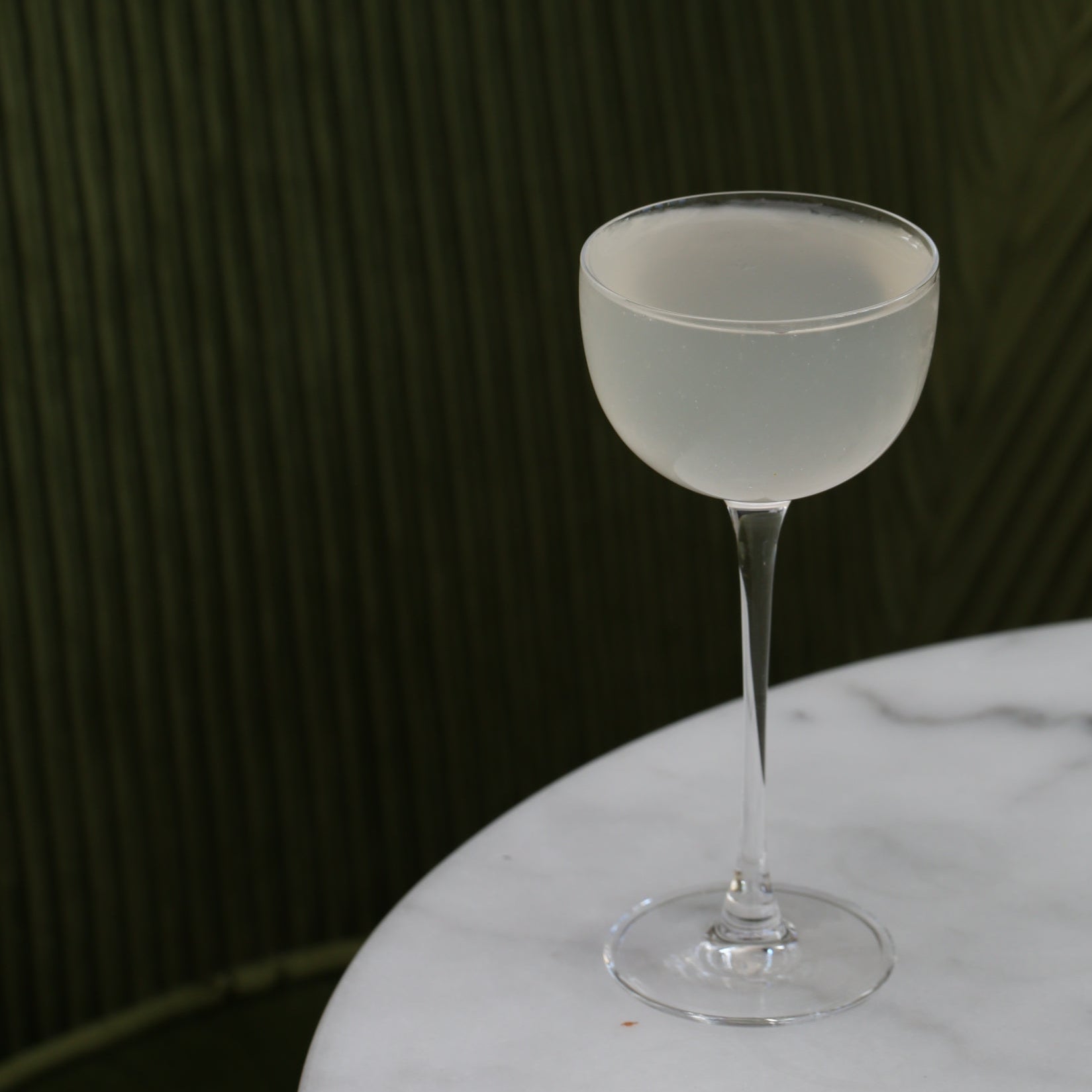 Frosted cocktail glass on a marble surface with a dark background