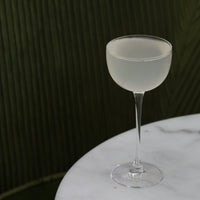 Frosted cocktail glass on a marble surface with a dark background