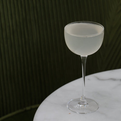 Frosted cocktail glass on a marble surface with a dark background